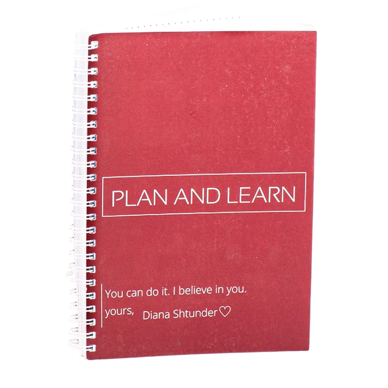 Червоний блокнот на білій пружині з написом «Plan and Learn»